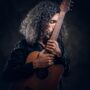 dark-photo-studio-curly-middle-aged-man-is-posing-with-guitar-photographer